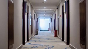 A long, narrow hotel corridor with doors on both sides and a patterned carpet.