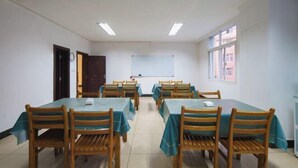 A conference room with six tables and chairs, a whiteboard, and a window.