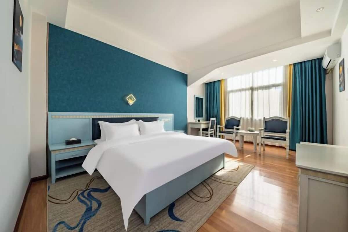 Una habitación de hotel con una cama grande, un escritorio y una silla.