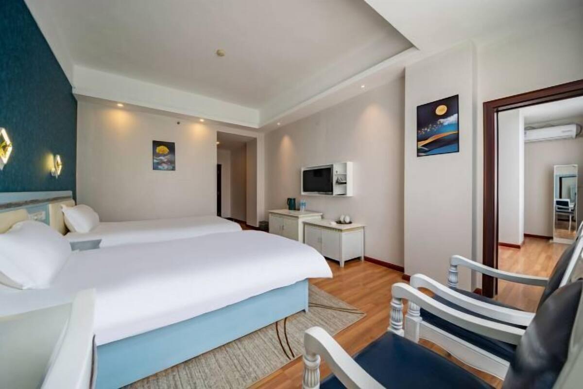 Una habitación de hotel con una cama grande, un escritorio con televisor y una silla.