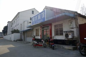 A building with a signboard, two motorcycles parked in front, and a clear sky. - Qingshui Hostel (Shanghai)