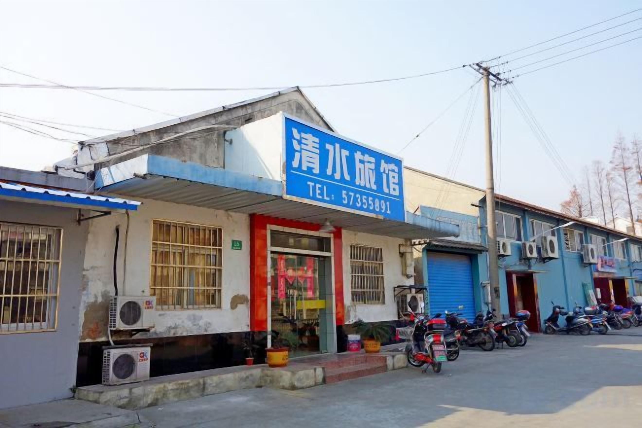 Un bâtiment avec une enseigne bleue, une porte rouge et une moto garée devant.