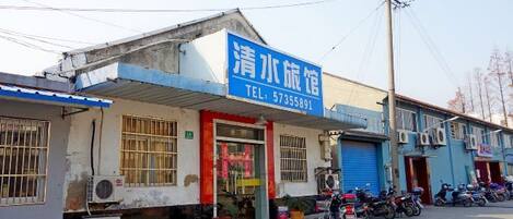 Edifício com placa azul, porta vermelha e uma motocicleta estacionada em frente.