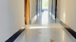 A hallway with a shiny tiled floor, a wooden door frame, and a view into another room. - Qingshui Hostel (Shanghai)