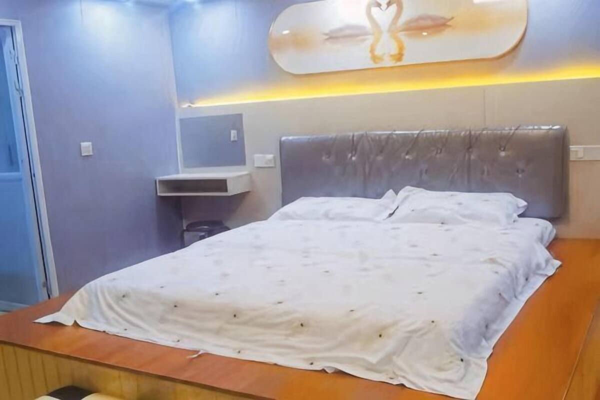 A bedroom with a bed, a headboard, a bedside table, and a wall-mounted shelf.