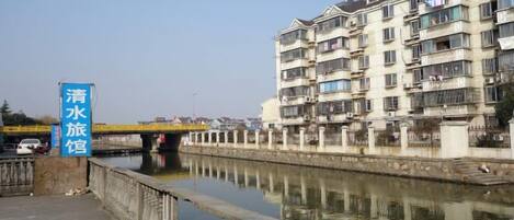 A canal with a bridge, a row of residential buildings, and a sign indicating a water station.