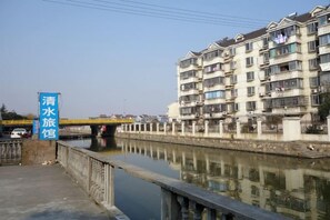 A canal with a bridge, a row of residential buildings, and a sign indicating a water station. - Qingshui Hostel (Shanghai)