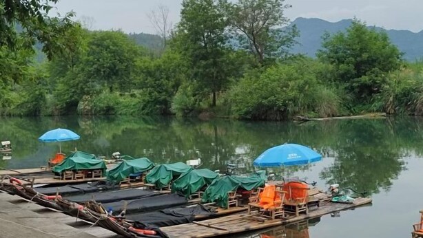 A riverside dock with canopies and seating, surrounded by lush greenery and mountains. - Yongjia Nanxi Jiangsenju Homestay (Yongjia)