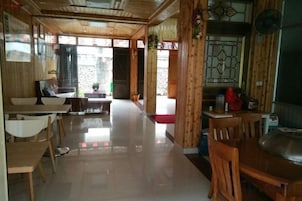 Un restaurante con mobiliario de madera, suelo de baldosas y vistas a través de un ventanal.