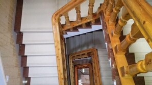 A wooden staircase with a handrail and a fire extinguisher on the wall. - Yongjia Nanxi Jiangsenju Homestay (Yongjia)