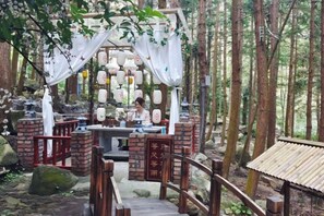 A traditional wooden structure with a brick base, surrounded by a forest. - Queen's Mountain Oxygen Heart Valley Mountain Resort (Lianshan)