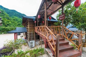 A traditional wooden building with a staircase leading to a covered porch. - Queen's Mountain Oxygen Heart Valley Mountain Resort (Lianshan)