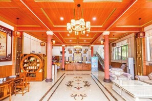 A hotel lobby with a wooden ceiling, a central chandelier, a reception desk, and a patterned floor. - Queen's Mountain Oxygen Heart Valley Mountain Resort (Lianshan)