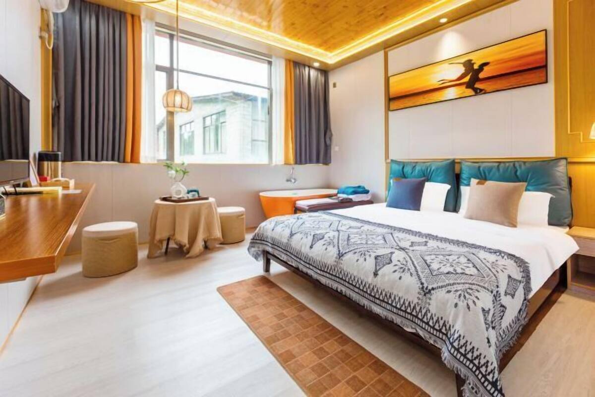 A modern hotel room with a large bed, a desk, and a view of the city.