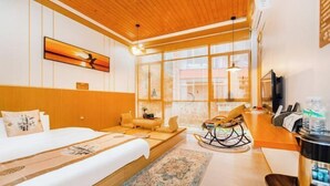 A hotel room with a bed, a rocking chair, a TV, and a kitchen area. - Queen's Mountain Oxygen Heart Valley Mountain Resort (Lianshan)