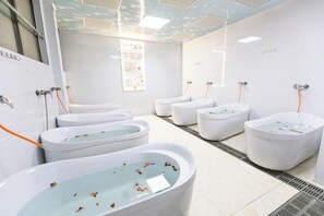 A modern bathroom with multiple white tubs, a tiled floor, and a ceiling with recessed lighting. - Queen's Mountain Oxygen Heart Valley Mountain Resort (Lianshan)