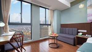 A hotel room with a large window, a desk with a chair, a sofa, a small round table with fruit, and a bed. - nanyuan e home hotel (liu an Railway Station Hotel ) ) (Lu'an)