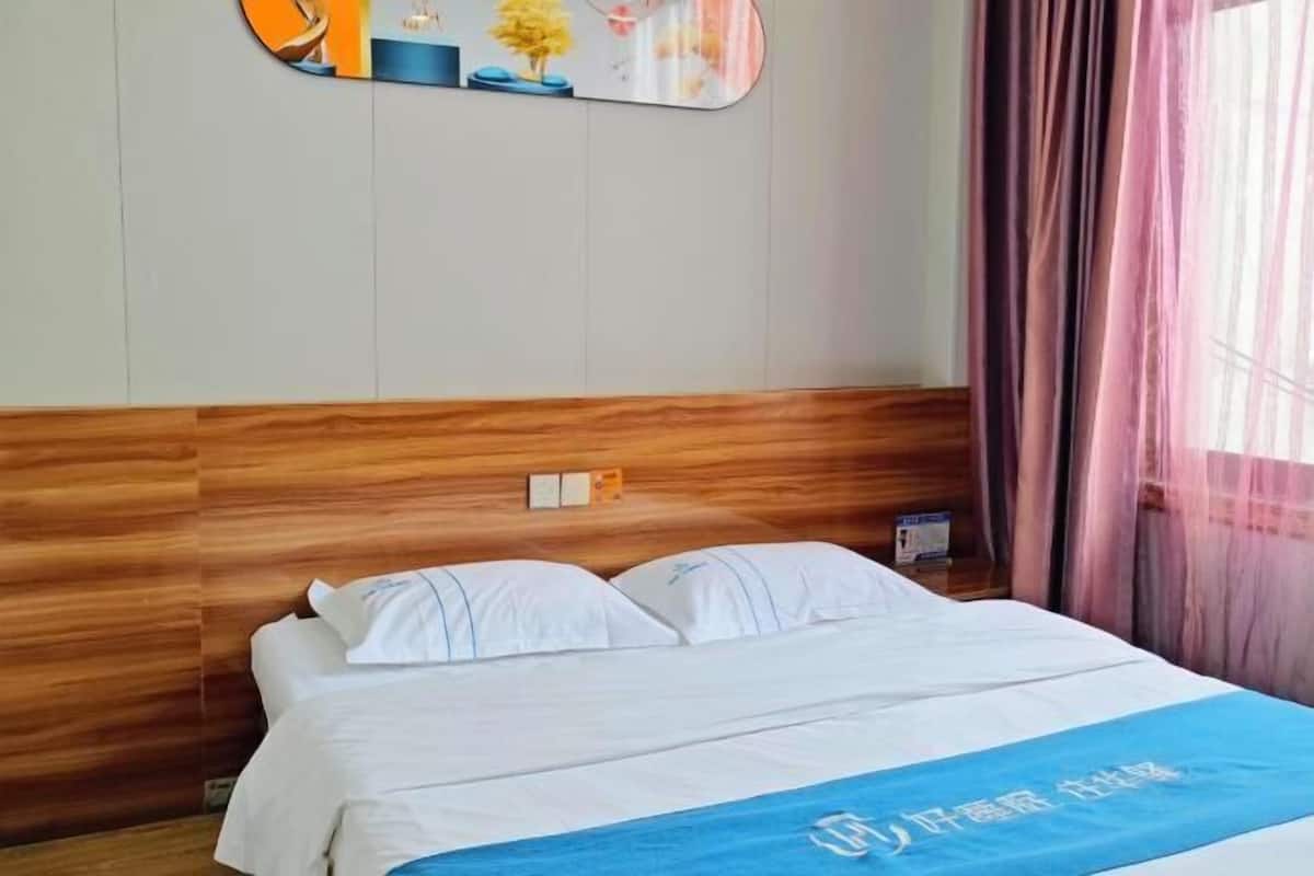 A hotel room with a wooden headboard, a bed with white linens, a blue towel, and a wall-mounted mirror.