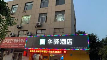 A hotel with a signboard displaying its name and a number of rooms.