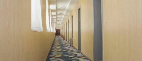 A long hallway with doors on both sides and a patterned carpet.