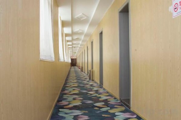 A long hallway with doors on both sides and a patterned carpet.