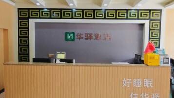 Mostrador de recepción con un cartel que indica el nombre del hotel, una computadora y un teléfono.