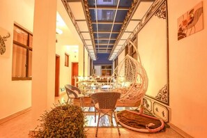 A corridor with a glass ceiling, a seating area with a chair and a table, and a decorative wall piece. - Loving Return · Cozy Stay Guesthouse（Dali Ancient Town, Yu'er Road Branch） (Dali City)