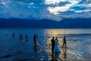 A wedding ceremony at a beach with a clear sky and mountains in the background. - Loving Return · Cozy Stay Guesthouse（Dali Ancient Town, Yu'er Road Branch） (Dali City)