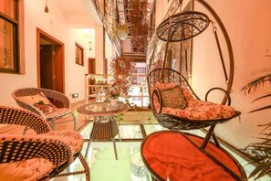 A cozy interior with wicker furniture, a glass table, and a staircase leading to an upper level. - Loving Return · Cozy Stay Guesthouse（Dali Ancient Town, Yu'er Road Branch） (Dali City)