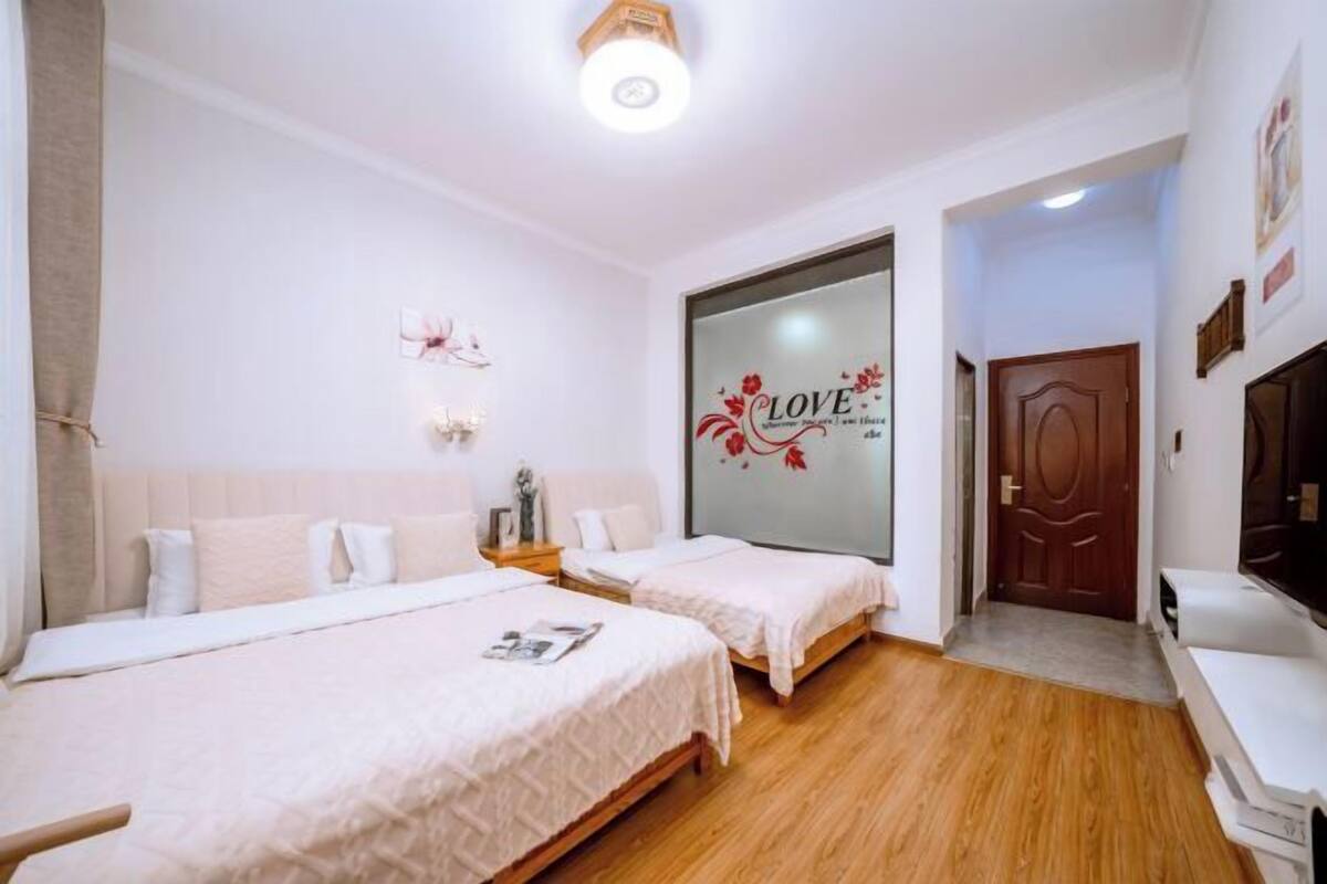 A hotel room with two beds, a wooden floor, a large mirror, and a door with a decorative design.