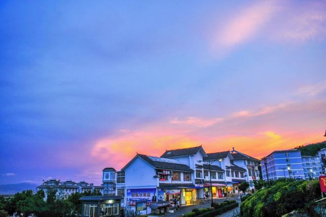 A coastal town with buildings, a clear sky, and a sunset.
