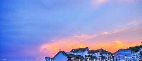 Un pueblo costero con edificios, cielo despejado y un atardecer.