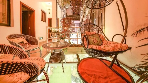 Une pièce meublée de meubles en osier, avec une table en verre et une vue sur un escalier.