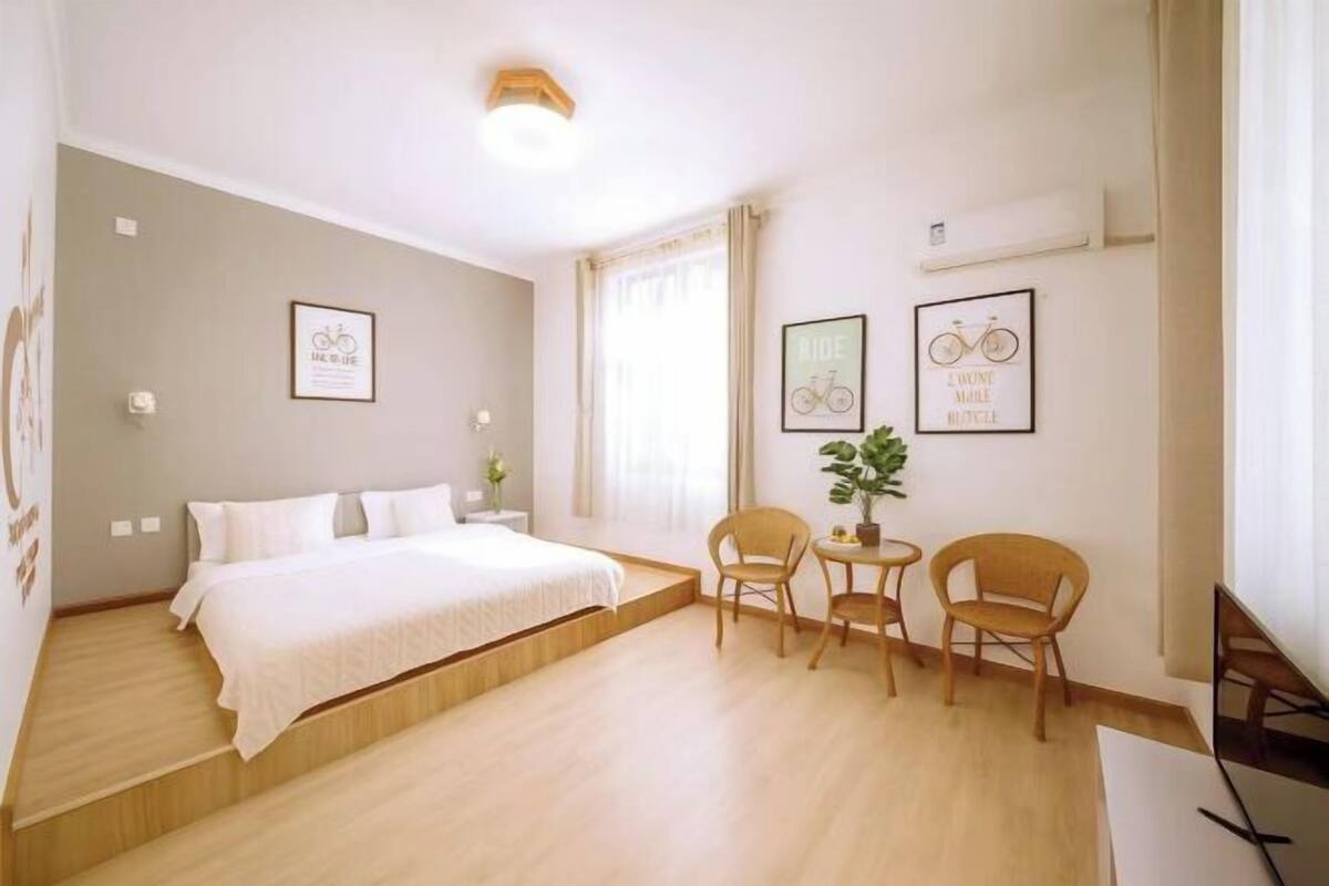 A hotel room with a bed, two chairs, a small table, and wall art.