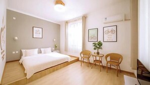 Une chambre d’hôtel avec un lit, deux chaises, une petite table et des œuvres d’art murales.