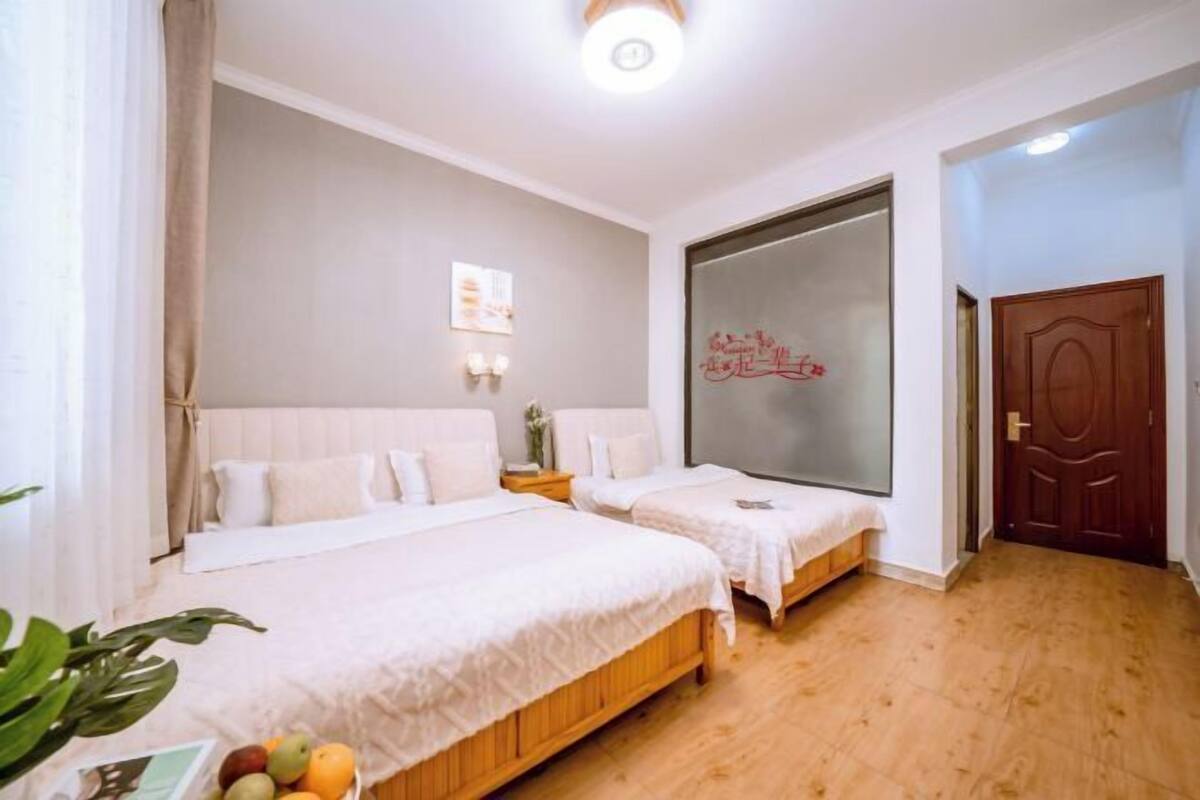A hotel room with two beds, a large mirror, a wooden floor, and a door.