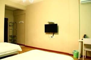 Camera d'albergo con due letti, una televisione a parete, un tavolino e un cestino.