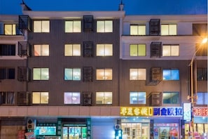 A multi-story building with multiple windows and balconies, featuring signage for various businesses on the ground floor.