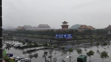A parking lot with vehicles, a traditional building with a pagoda-style roof, and a sign with Chinese characters.
