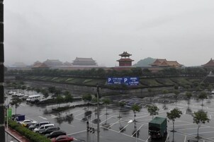 Un estacionamiento con vehículos, un edificio tradicional con techo al estilo pagoda y un letrero con caracteres chinos.