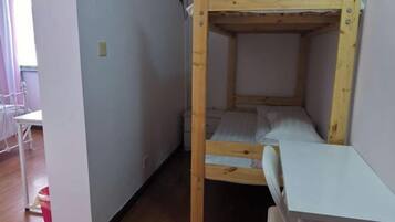 Una cama litera con escritorio y silla, pared blanca y suelo de madera.