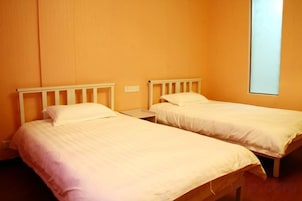 Dos camas individuales con cabeceros de madera en una habitación con paredes anaranjadas.