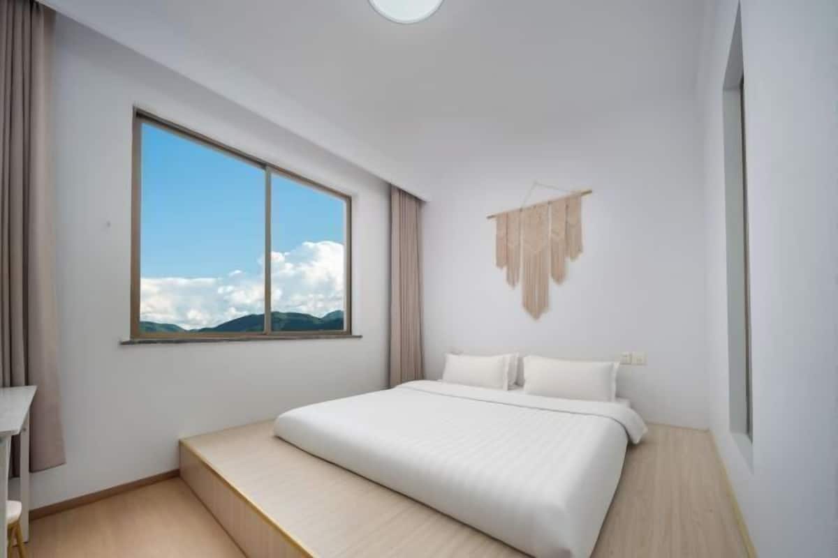 A modern bedroom with a large window, a bed, and a small desk.