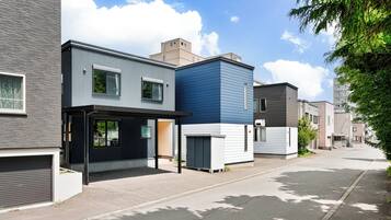 Eine moderne Wohnstraße mit zeitgemäßen Häusern, wolkenlosem Himmel und einem von Bäumen gesäumten Bürgersteig.