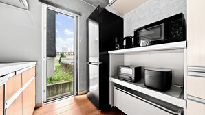 A compact kitchen with a built-in microwave, coffee maker, and a small refrigerator. - THE GRACIOUS (Sapporo)