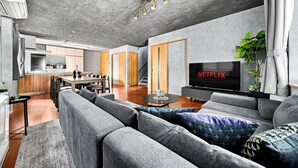 A modern living room with a large sofa, a coffee table, and a flat-screen TV displaying 'NETFLIX'. - THE GRACIOUS (Sapporo)