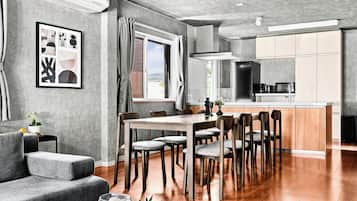 Cuina moderna amb una illa central, terres de fusta i una zona de dinar amb taula i cadires.
