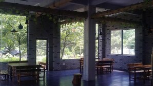 A spacious room with brick walls, large windows, and wooden furniture. - Yellow Cloth Reflection Inn (Yangshuo)