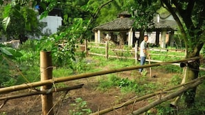 A bamboo fence in a rural setting with a small traditional house in the background. - Yellow Cloth Reflection Inn (Yangshuo)