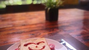 A slice of bread with a heart drawn on it, placed on a white plate with a cherry and a slice of tomato. - Yellow Cloth Reflection Inn (Yangshuo)